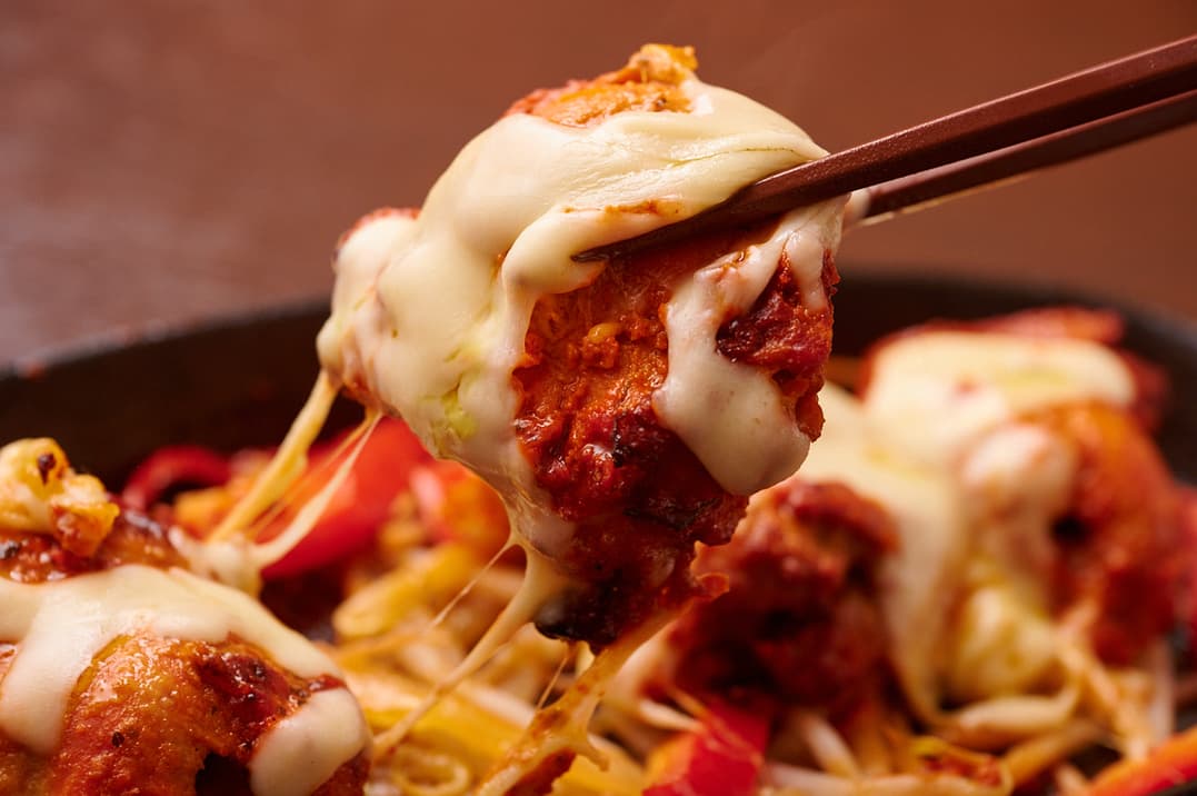 さくらアジアンダイニング&バーの箸で持ち上げたチーズのせグリルチキンと野菜